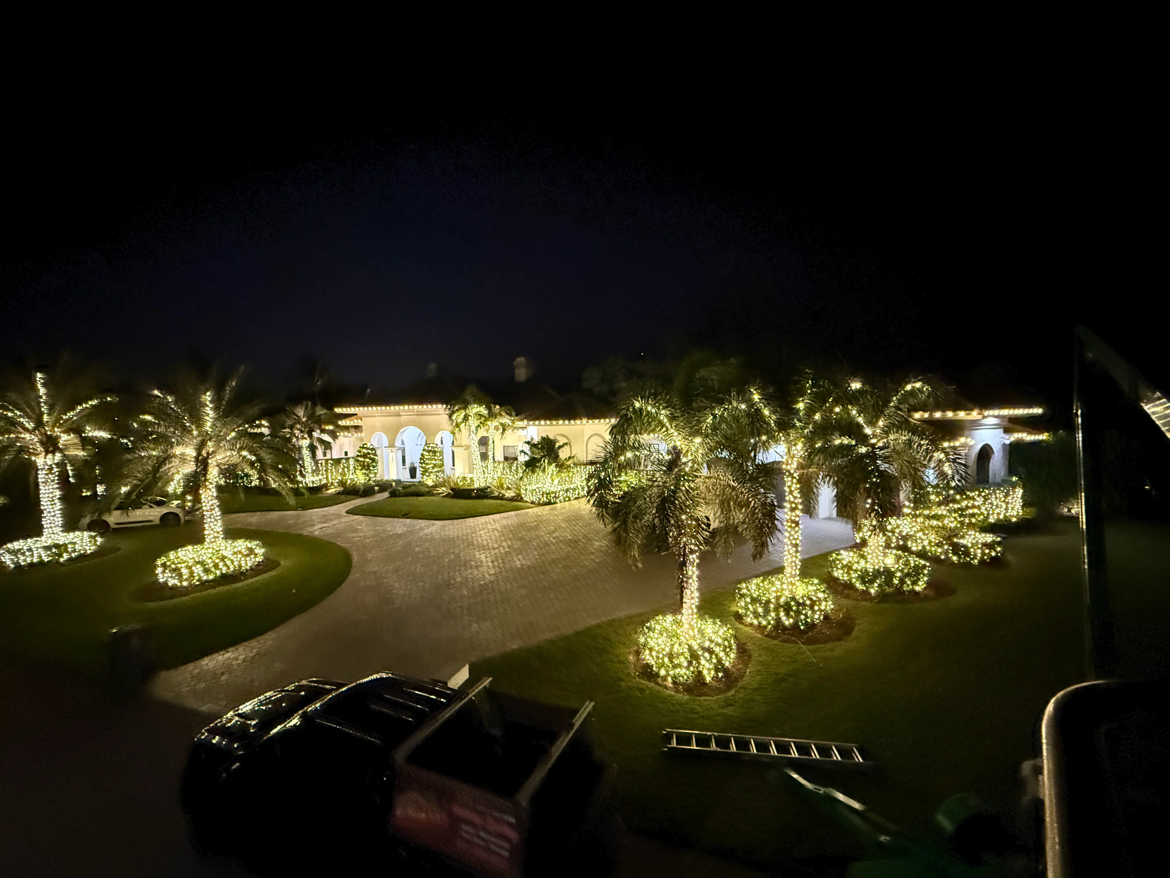 Aerial view of luxury estate with comprehensive warm white lighting throughout property