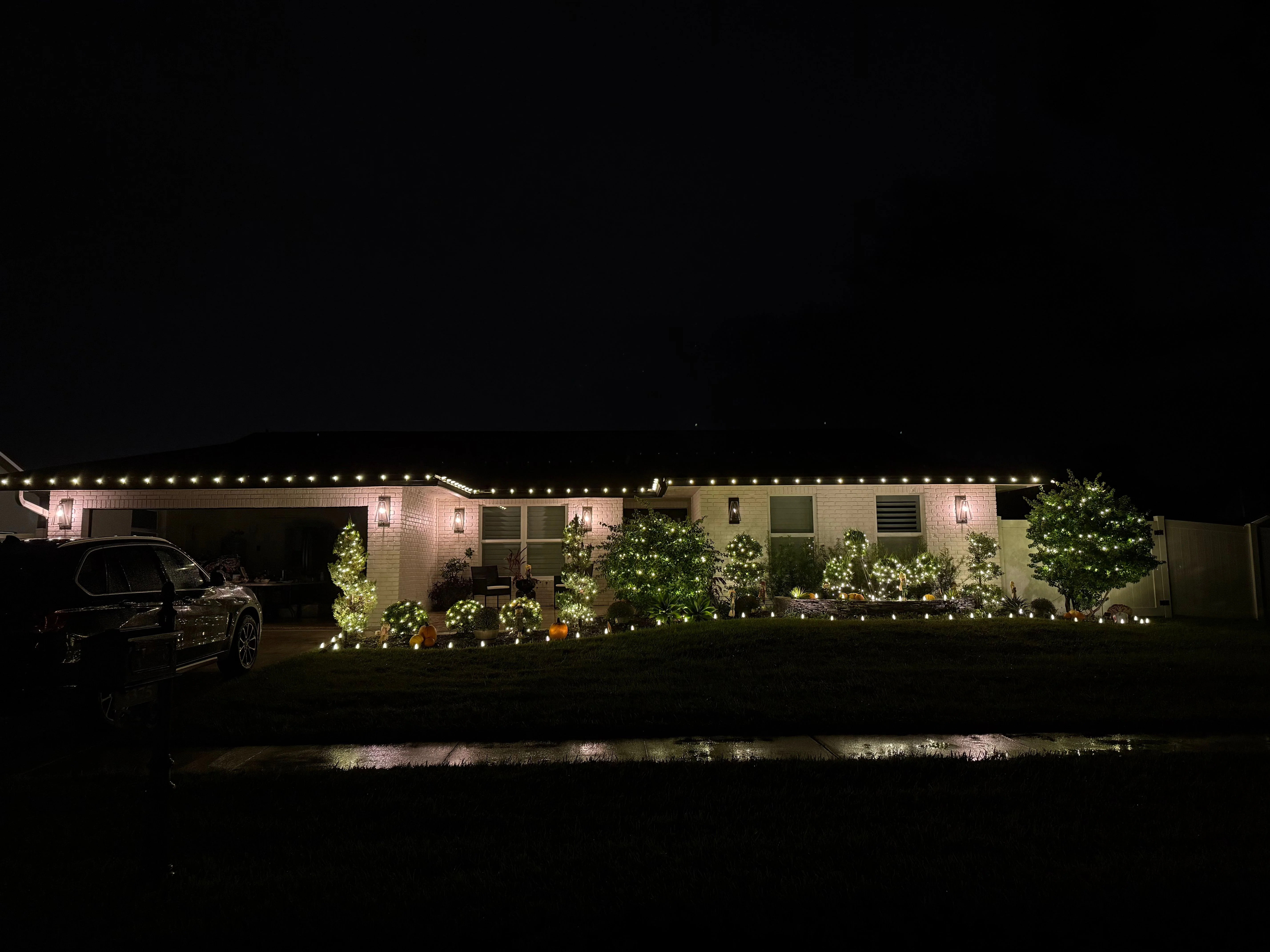 Single-story ranch house with warm white roofline lighting and professional landscaping illumination